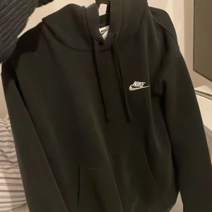 Svart hoodie från Nike - Säljer en klassisk svart hoodie från Nike med vit logga på bröstet. Den har en bekväm passform med känguruficka och justerbar huva. Perfekt för en avslappnad stil.