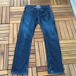 Blå jeans från Acne Jeans - Snygga blå jeans från Acne Jeans med klassisk design. De har en rak passform och är tillverkade i denim med fyra fickor och knappgylf. Perfekta för en stilren look. Slitningen är inte gjord pågrund av att dem är använda utan det är en del av designen! Kan mötas upp och lämna i Stockholm men annars betalar köpare pris för frakt!