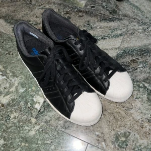 Adidas Superstar 82 - Säljer dessa sjukt snygga Superstars då de inte riktigt passar mig i storleken. Endast använda ett fåtal gånger och i mycket fint skick. Skokartong och prislapp medföljer. Nypris: 1500 kr – därav priset. Hör av er vid ytterligare frågor!