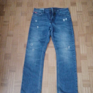 Blå jeans från Lee Cooper - Snygga blå jeans från Lee Cooper i klassisk stil. De har en straight passform och är tillverkade av 100% bomull. Jeansen har en sliten look med små revor för en trendig touch. Perfekta för en avslappnad stil.