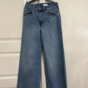 Blå jeans från H&M - Snygga blå jeans från H&M med en avslappnad wide fit. De har en klassisk femficksdesign och är tillverkade i 100% bomull för en bekväm känsla. Perfekta för en casual look.