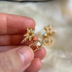 Guldörhängen med pärlor - Snygga guldörhängen med stjärnformad design och dekorerade med små pärlor. Perfekta för att ge en elegant touch till din outfit.