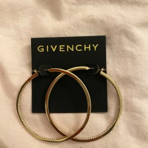 Guldiga hoop-örhängen från Givenchy - Snygga guldiga hoop-örhängen från Givenchy med glittriga detaljer längs kanten. Perfekta för att ge en elegant touch till din outfit. Kommer på originalkortet.