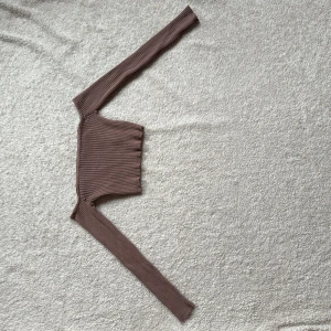 Brun ribbad offshoulder topp från Zara - Säljer en snygg brun ribbad offshoulder topp från Zara. Toppen har långa ärmar och en croppad passform som ger en trendig look. Perfekt för att styla med höga jeans eller kjol. Storlek M, men passar S också.