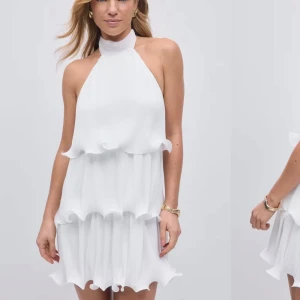 Vit student ärmlös klänning med volanger - Säljer en stilren vit klänning med halterneck och volanger. Klänningen är ärmlös och har en knytning i nacken som ger en elegant touch, den är helt ny bara testad. Perfekt för studenten!