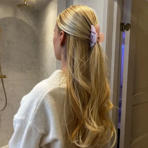 Rosa hårklämma med texten 'Love' - Söt rosa hårklämma med pärlbroderad text 'Love'. Perfekt för att ge en romantisk touch till din frisyr. Klämman har en skimrande yta som fångar ljuset fint. Lila/vinröd text. Oanvänd, endast testad för bilden!