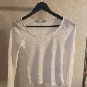 Vit ribbad långärmad topp m. spets  - Säljer en stilren vit ribbad topp med långa ärmar. Spets krage. Aldrig andvänd, bara tagit bort prislappen. Strl. Xs från lager 157. Säljes för 30 kr