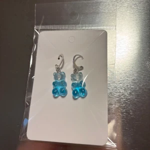 Blå örhängen med björndesign - Söta örhängen med björndesign i blått. Perfekta för att lägga till en lekfull touch till din outfit. De är lätta och bekväma att bära hela dagen. (Billigt material) 