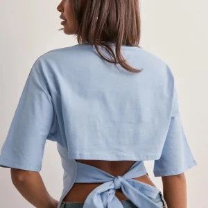 Ljusblå croppad topp med knyt - Säljer en ljusblå croppad topp med korta ärmar och snygg knytning i ryggen. Slutsåld i denna färg !