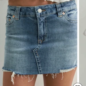 Blå jeanskjol Nelly - Snygg blå jeanskjol från Nelly med kort passform och rå, fransig kant nedtill. Klassisk femficksdesign, knapp och dragkedja framtill. Perfekt för dig som gillar en avslappnad och trendig stil. Nypris är 500 och är helt slutsåld! Min är använd max 5 ggr!