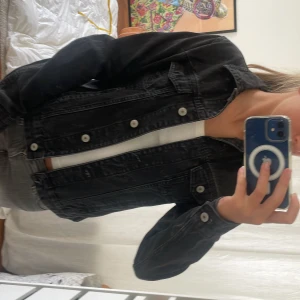 Svart jeansjacka från Denim Co - Snygg svart jeansjacka från Denim Co med klassisk krage, silverfärgade knappar och två bröstfickor med lock. Jackan har en cool tvättad look och raka långa ärmar. Perfekt att slänga över en t-shirt för en chill vibe.