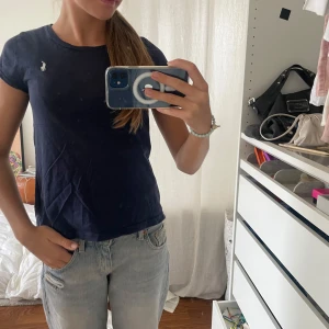 Mörkblå t-shirt från Polo Ralph Lauren - Snygg mörkblå t-shirt från Polo Ralph Lauren med klassisk rund hals och korta ärmar. T-shirten har den ikoniska broderade loggan i vitt på bröstet och är gjord i mjuk bomull. Perfekt för en chill och stilren look.