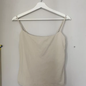 Beige linnetopp från Gina Tricot - Supersnygg beige linnetopp från Gina Tricot, Basically Basics-kollektionen. Tunn och mjuk i bomullsmaterial med justerbara smala axelband. Enkel och clean design som är lätt att matcha med allt. Perfekt för varma dagar och chill vibes.