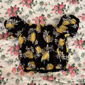 Offshoulder topp - En svart offshoulder topp från Gina Tricot i strl XS med gula citroner och vita blommor. Puffiga korta ärmar och elastisk kant vid axlar och midja!💞
