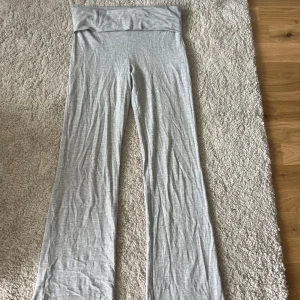 Gråa lågmidjade mjukisbyxor - Snygga grå mjukisbyxor med bred, låg midja och utsvängda ben. Byxorna är gjorda i mjukt bomullsmaterial och har en chill, loose passform som är perfekt för att hänga hemma eller dra till gymmet. Enkel design utan detaljer, passar dig som gillar stilren och bekväm look.