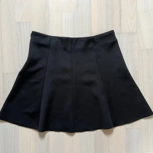 Svart miniskjol  - Minikjol i halvt glansigt, svart tyg. Är i barnstorlek, men passar XS bra! Perfekt till strumpbyxor och en kofta på hösten, eller som basplagg till fest. Kjolen har en dragkedja i sidan för att kunna tas på smidigt, och är lite lätt klockad utåt. Säljer för att den inte passar mig längre!