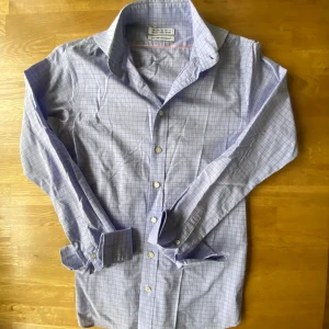 Blårutig skjorta från The Shirt Factory - Snygg extra slim fit skjorta designad av Linnéa Braun med blårutigt mönster och diskreta rosa linjer. Materialet är lättskött bomull som är enkel att stryka. Kräver manschettknappar (ingår ej)