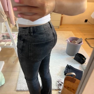 Svarta bootcut jeans med låg midja - Snygga svarta jeans med lätt tvättad look och bootcut-ben. Modellen har låg midja och klassiska fem fickor. Jeansen är gjorda i ett stretchigt denim-material som sitter skönt och framhäver figuren. Perfekta för dig som gillar en cool och avslappnad stil.