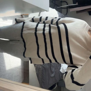 Randig beige stickad tröja Vero Moda - Säljer en beige stickad tröja från Vero Moda i storlek XS. Tröjan har svarta horisontella ränder, rund hals och långa ärmar. Den har en loose passform och är perfekt för chill dagar. Materialet är mjukt och skönt mot huden.