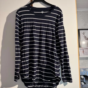 Marinblå tröja med vita ränder  - Snygg marinblå långärmad tröja från C med vita horisontella ränder. Tröjan har rund hals och är gjord i mjuk bomull, perfekt för chill dagar. Passformen är normal och den har lite längre bakstycke för en cool look.