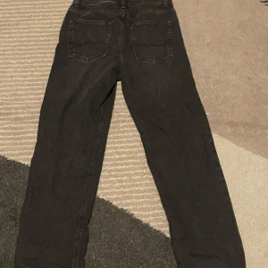 Svarta jeans från Jack & Jones, 158 - Säljer ett par svarta jeans från Jack & Jones i storlek 158, passar dig som är runt 13 år. Klassisk femficksmodell med raka ben och normal passform. Jeansen har snygga bakfickor med diskret söm och är gjorda i slitstarkt denimtyg.