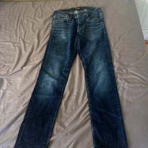 Jack & Jones Slim Glenn blå jeans - Snygga Slim Glenn jeans från Jack & Jones i mörkblå tvätt med klassiska fem fickor och smal passform. Jeansen har slitningar och kontrastsömmar, tillverkade i bomull med lite stretch för extra komfort. Perfekta för dig som gillar en modern och stilren look.