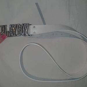 Vitt bälte Playboy - Stort bältesspänne med logga i silver och strass  Lädermaterial med tunt ytskikt (ej fullnarvsläder), men fortfarande äkta läder med beläggning  Ursprungligen storlek L (ca 90–100 cm) men har modifierats till XS  Passar höft ca 78–80 cm, midja ca 56 cm (har gjort 2 extra hål) 💌 Skriv gärna med prisförslag eller om du har några frågor! 😄✨
