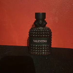 Valentino born in Roma edt  - Säljer en lyxig parfym från Valentino i en mörk, nitprydd glasflaska med svart etikett och rosa text. Perfekt för dig som gillar en fräsch och aromatisk doft. Sprejad ca 10 gånger. Öppen för byten!