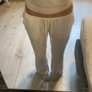 Vita linnebyxor - Säljer ett par lågmidjade vita linnebyxor med avslappnad passform och snörning i midjan. Byxorna har raka ben och praktiska sidofickor. Perfekta för chill dagar eller när du vill ha en luftig och skön stil. Passar dig som gillar enkel och clean look. Dem är även stretchiga i midjan💕💕