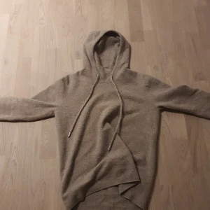 Beige kashmir hoodie - Säljer en mysig beige stickad hoodie med långa ärmar och justerbar huva. Perfekt för kyliga dagar och ger en avslappnad look. Passar bra till jeans eller leggings.