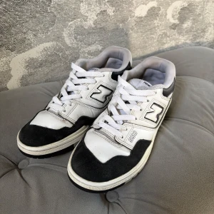 New Balance 550 sneakers i svart och vit - Säljer ett par New Balance 550 sneakers i klassisk svart och vit färgkombination. Skorna har snörning och en robust sula med bra grepp. Perfekta för en stilren och sportig look.