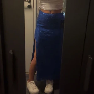Blå glittrig kjol från NA-KD - Snygg blå glittrig långkjol från NA-KD med en slits på sidan. Perfekt för att sticka ut på festen! ✨