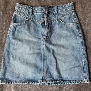 Jeanskjol med knappar - Snygg jeanskjol i klassisk blå denim med knappar framtill och praktiska fickor både fram och bak. Kjolen är från Gina Tricot i storlek 36. Kjolen är i mycket bra skick. Säljer den eftersom den  kommer inte längre till användning. 