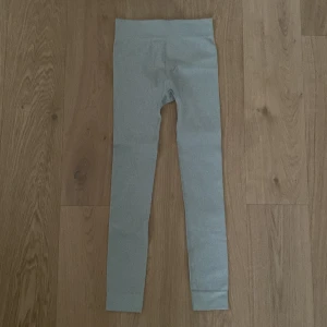 Grå ribbade leggings från H&M - Säljer ett par grå ribbade leggings från H&M i storlek XS. De har en tight passform och är perfekta för en bekväm och stilren look. Materialet är mjukt och stretchigt för extra komfort.