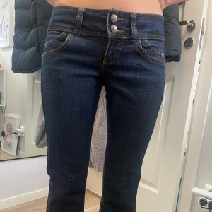 Mörkblå jeans med dubbelknäppning - Snygga mörkblå jeans med dubbelknäppning och kontrastsömmar. De har en klassisk femficksdesign och en smickrande passform. Perfekta för en stilren look.