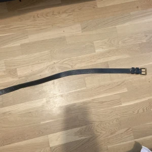 Svart bälte med silverfärgat spänne - Snyggt svart bälte med ett stilrent silverfärgat spänne. Perfekt för att ge en extra touch till din outfit. Bältet har en klassisk design och passar till många olika stilar.