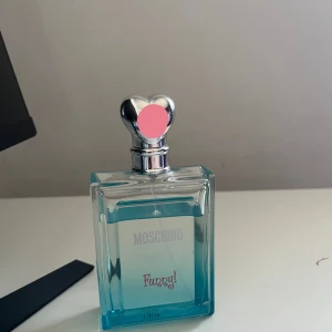 Moschino Funny! Parfym - Fräsch och lekfull parfym från Moschino i en stilren, rektangulär flaska med en hjärtformad silverfärgad kork. 