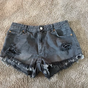 Grå jeansshorts från Bershka - Säljer ett par grå långmidjade jeansshorts från Bershka med slitna detaljer eftersom jag vuxit ur dem. Använda fåtal gånger🙌🏽