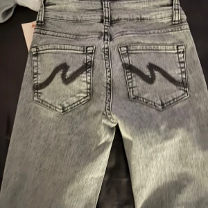 Grå jeans från Nelly - Snygga grå jeans från Nelly med en cool tvättad look. De har en klassisk femficksdesign och en unik svart detalj på bakfickorna. Perfekta för en stilren vardagslook. De är helt nya, aldrig använda med etikett kvar på. Ordinarie pris 699 kr på Nelly.com 