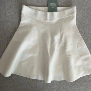 Vit kjol från H&M - Snygg vit kjol från H&M i en skön och stretchig passform. Kjolen har en ribbad midja och är tillverkad av 72% Lenzing Ecovero viskos, vilket gör den både bekväm och miljövänlig. Perfekt för en stilren look!