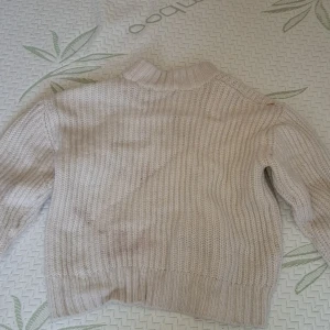 Beige stickad tröja - Säljer en mysig beige stickad tröja från 157. Tröjan har en hög krage och långa ärmar, perfekt för kyliga dagar. Den ribbade strukturen ger en klassisk look. Storlek 150. Köpte runt 100-200 kr