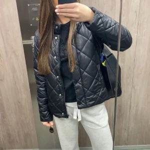 Svart jacka - Snygg svart quiltad jacka med knappar. Perfekt för en stilren look. Jackan har en normal passform och är långärmad, vilket gör den idealisk för kyligare dagar.