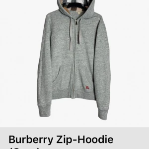 Grå zip-hoodie från Burberry - Säljer en stilren grå zip-hoodie från Burberry. Den har en dragkedja framtill och en klassisk huva med Burberrys ikoniska mönster på insidan. Tröjan är i storlek s och är köpt från storeenda. Priset kan diskuteras vid en snabb affär