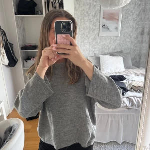 Grå stickad tröja - Säljer en mysig grå stickad tröja med långärmad design. Perfekt för kyligare dagar och enkel att matcha med olika outfits. Tröjan har en avslappnad passform och är idealisk för både vardag och avslappnade tillfällen.