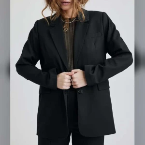 Svart kavaj - Snygg svart kavaj med klassisk design och knappar framtill. Perfekt för en stilren look. Långärmad med en normal passform.