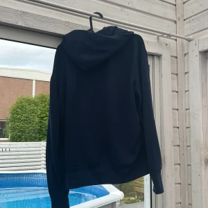 Mörkblå hoodie från Ralph Lauren - Säljer en mörkblå hoodie från Polo Ralph lauren med vita snören. Tveka inte på att höra av dig om du har några funderingar! Kan även tänka mig att byta emot andra plagg