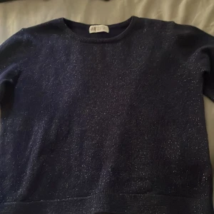 Mörkblå glittrig tröja  från H&M - Supersnygg mörkblå tröja från H&M med glittriga trådar i tyget. Med utsvängda ärmar.