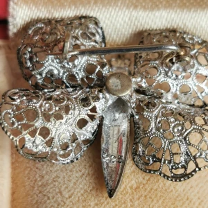 Vintage brosch i form av fjäril - Unik brosch i silverfärgad metall formad som en fjäril med detaljerat filigranmönster på vingarna. Perfekt accessoar för att ge din outfit en elegant touch. Kom med förslag om pris,se bild. 