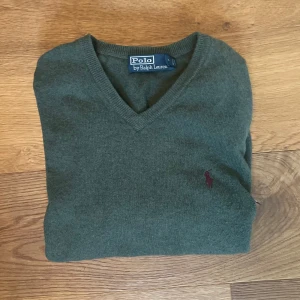  tröja Polo Ralph Lauren - Mörkgrön v-ringad tröja från Polo Ralph Lauren i mjuk ullmix. Perfekt för lager-på-lager och snygg till det mesta! Passar perfekt en sen sommarkväll🙌 hör av er vid minsta fundering👍