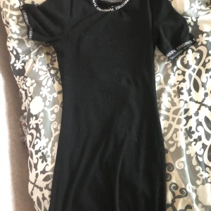 Svart kortklänning från H&M  - Svart kortklänning från H&M med texten 'ORIGINAL' i vitt runt halsringning och ärmslut. Klänningen har en enkel, tight passform och är tillverkad i mjukt, stretchigt material. .